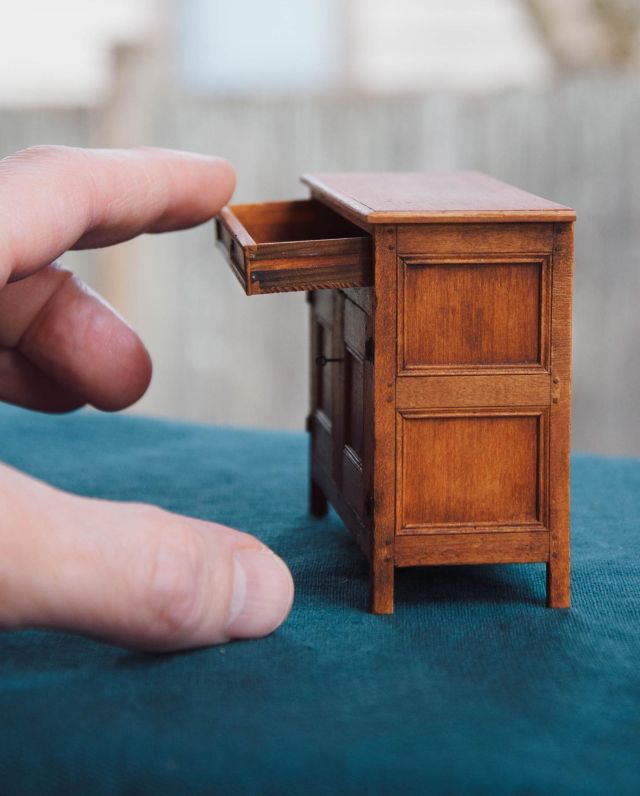 My 1/12th scale Virginia Low Cupboard is made from pear wood, reclaimed Pacific Northwest Douglas Fir (likely old-growth) and reclaimed poplar. In my class, we built this cupboard using joinery techniques just like the original full-size piece (with some terrific modern tools.)

The original circa 1680-1710 cupboard, in the collection of DeWitt Wallace Decorative Arts Museum at Colonial Williamsburg, predates the era of cabinetmaking in America. Case furniture of this period was produced by joiners, the same artisans that built simple boxes, joint stools, and other wood-framed structures. 

The cupboard is built of panels set within a boxlike framework of stiles and rails. The joints of the mortised-and-tenoned frame are secured with wooden pins. My students used draw plates to make very tiny .031” diameter dowels to use as joinery pins in 1/12th scale!

The single drawer is mostly constructed with simple butt joints like the original was, but it includes a single large dovetail on the front of each side (and tiny nails). It also has a dado cut into either side so that the drawer can glide on small rails set inside of the cupboard.

#craiglabenzminiatures